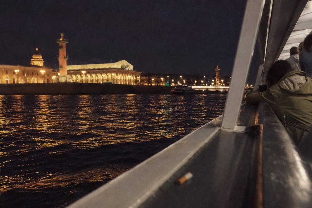Illuminated Parisian monuments reflecting in the Seine at night from a boat deck, no text, no logos, no people