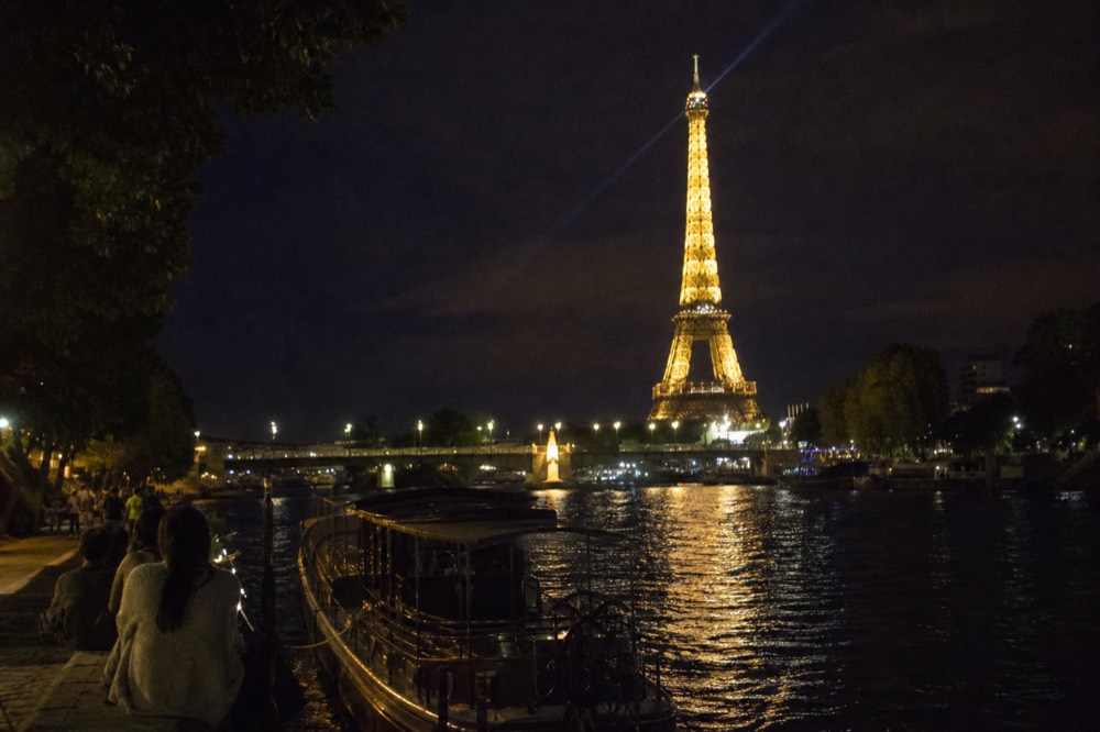 The illuminated Eiffel Tower sparkling above the Seine at night, reflections on the river surface, no text, no logos, no people