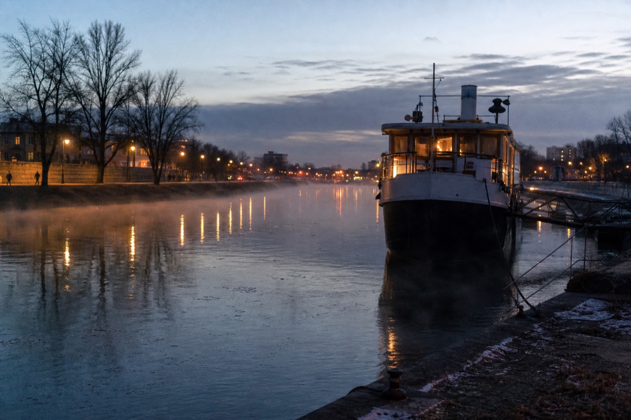 A Paris riverboat moored on the Seine at dusk, city lights reflecting on the water, no text, no logos, no people