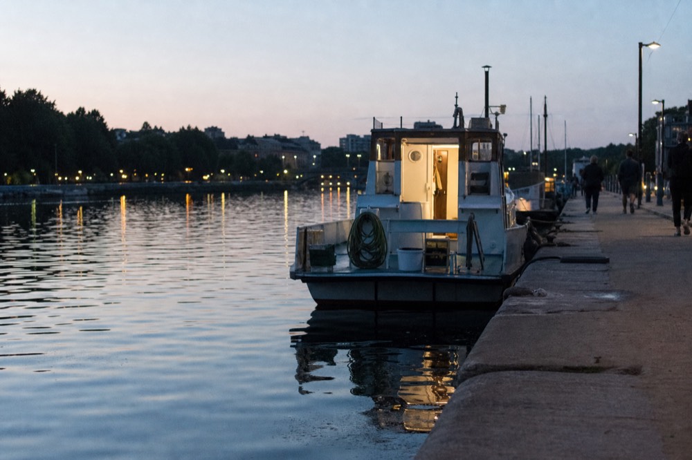 Lit riverbank and boat lights along the Seine on a summer evening, no text, no logos, no people