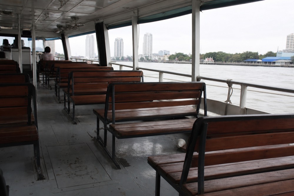 Covered interior of a glass-sided river shuttle with bench seating facing the water, no text, no logos, no people
