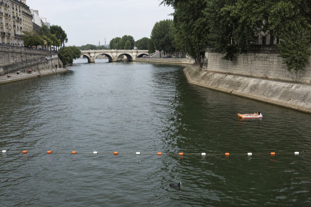 Marked swimming zone with buoys on a calm side channel of the Seine, no text, no logos, no people