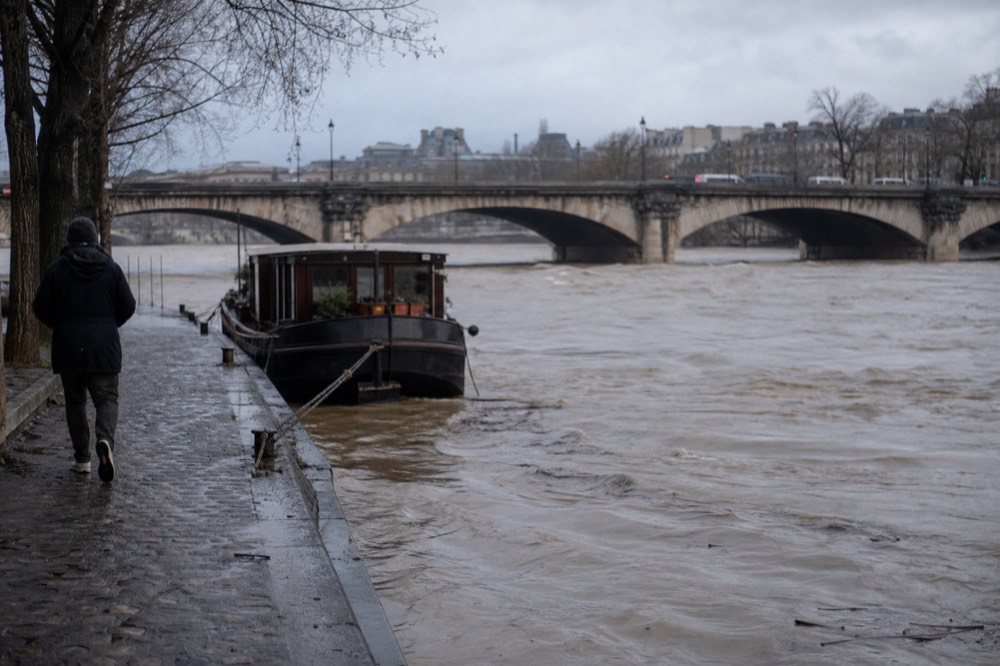 The Seine flowing between stone bridges under a grey Paris sky, no text, no logos, no people
