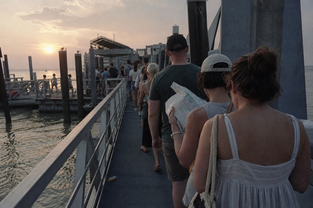 Crowded boarding queue at a Seine cruise pontoon on a summer evening, no text, no logos, no people