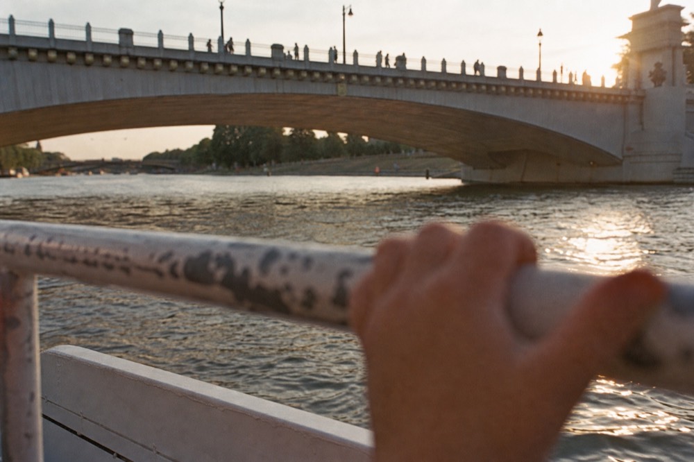 Child's view from a boat rail of the Seine and a Paris bridge, no text, no logos, no people.