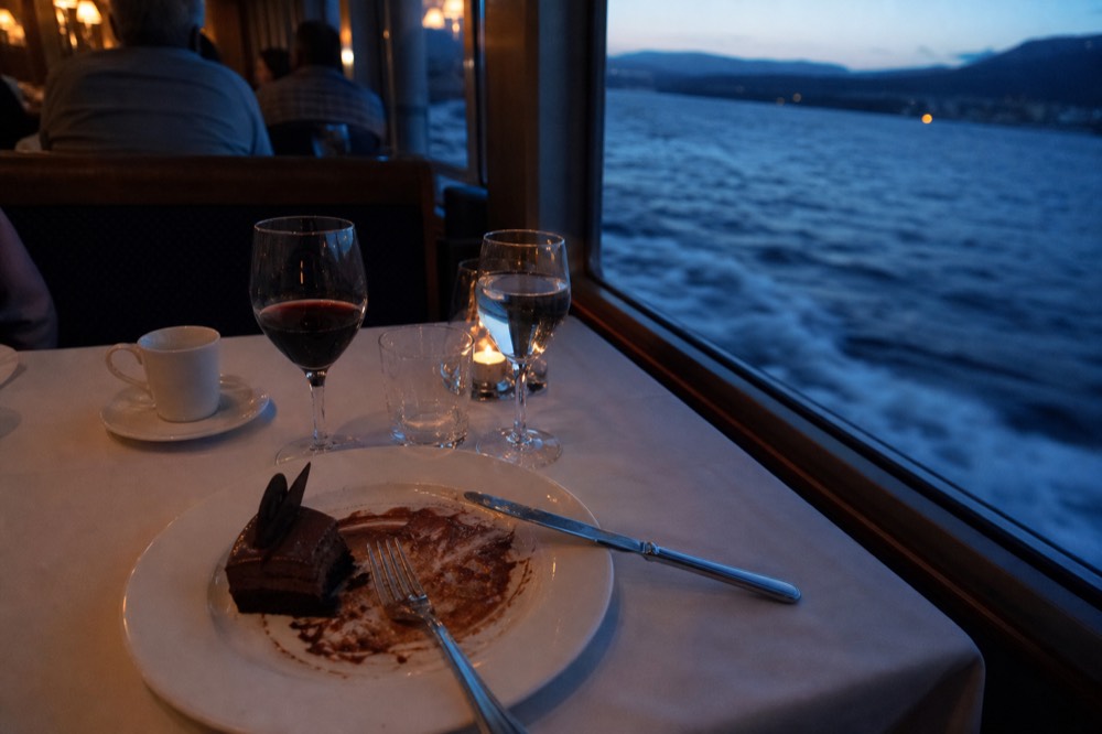 Plated three-course gourmet dinner with dessert course on a white tablecloth aboard a river cruise, no text, no logos, no people